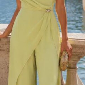 May include: A light lime green one-shoulder jumpsuit featuring a draped bodice, a fitted waist with a decorative silver-toned accent, and wide-leg trousers with an integrated wrap-style overlay panel that extends to the floor.