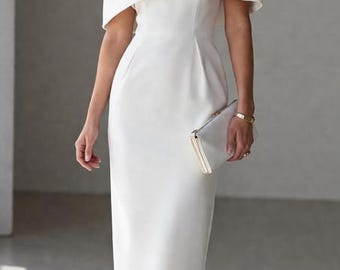 May include: A white midi dress with a cape-like overlay. The dress features a fitted silhouette and is paired with white heels and a clutch. The overall style is elegant and suitable for formal events.