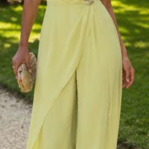 May include: A light lime green one-shoulder jumpsuit featuring a draped bodice, a gathered waist detail with a metallic accent, and wide-leg trousers with an overlay panel that creates a skirt-like appearance. The fabric has a smooth texture.