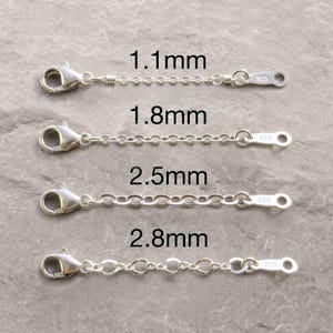 May include: Four silver jewelry extender chains with lobster claw clasps, each marked 925. The chains are labeled with widths of 1.1mm, 1.8mm, 2.5mm, and 2.8mm. These metal components are designed for adjusting the length of necklaces or bracelets.