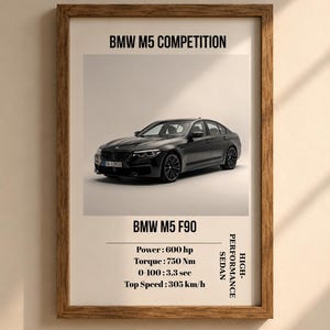 May include: A framed poster featuring a dark grey BMW M5 Competition saloon. The text reads BMW M5 COMPETITION, BMW M5 F90, Power: 600 hp, Torque: 750 Nm, 0-100: 3.3 sec, Top Speed: 305 km/h, and HIGH-PERFORMANCE SALOON in black lettering on a white background.