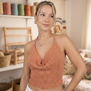 May include: A peach-colored crochet top with a halter neck and cowl neckline. The top is part of a DIY summer fashion pattern, as indicated by the text "The 'Luise' Crochet Top Pattern" and "Easy DIY Summer Fashion | PDF Download".