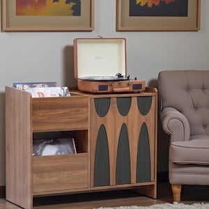 May include: A wooden record player cabinet with a built-in record player and storage for vinyl records. The cabinet has a mid-century modern design with a brown finish and black accents. The record player is brown and has a handle. The cabinet is 30 inches tall.