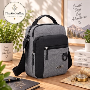 May include: A grey and black crossbody bag with a top handle, multiple zippered compartments, and a black D-ring. The bag features a rectangular metal tag with the text JINGPIN on the front lower section and includes an adjustable strap.