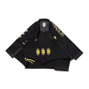 Puede incluir: Uniforme negro de artes marciales con detalles amarillos. El conjunto de chaqueta y pantalón presenta diseños y texto bordados en amarillo. El uniforme se muestra sobre un fondo blanco.