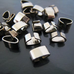 Puede incluir: Un montón de terminales de crimpado de metal plateado para la elaboración de joyas.