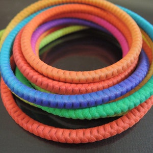 Puede incluir: Un conjunto de seis cordones trenzados de colores en colores arcoíris, incluyendo rojo, naranja, amarillo, verde, azul y morado.