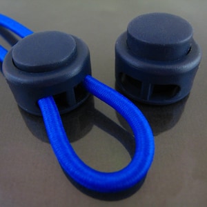 May include: Two dark blue plastic cord stoppers with a blue elastic cord threaded through one of them.