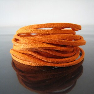 May include: A close-up of a spool of orange leather cord. The cord is soft and supple, and it is perfect for crafting projects.