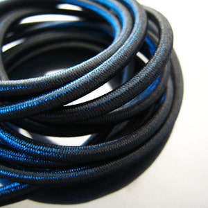 May include: Black elastic cord with a thin blue stripe running along the edge. The cord is coiled and ready to be used for crafting projects.