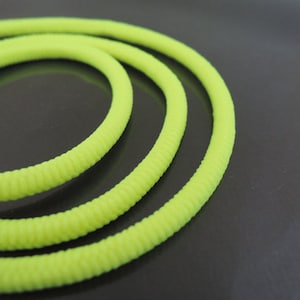 Puede incluir: Un cable flexible, acanalado, de color amarillo brillante, enrollado en un círculo.