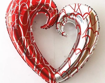 Puede incluir: Dos globos de corazón de aluminio, uno rojo y otro plateado, están entrelazados para formar un solo corazón. Ambos globos tienen un patrón de corazones blancos y rojos.