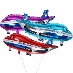 May include: Three foil airplane balloons in red, blue, and purple. The balloons are shaped like airplanes with white accents and are tied together with strings.