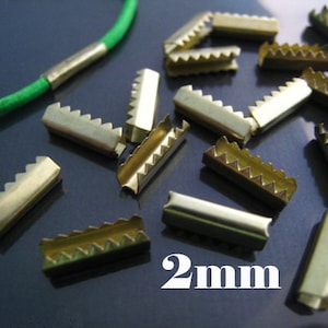May include: A close-up of 20 gold metal 2mm slider buckles. The buckles have a serrated edge and are ideal for making straps, belts, or other crafts.