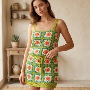 May include: A green crochet top and skirt set with a square pattern in orange, teal, and cream. The top has wide straps, and the skirt has a drawstring waist. The set is made of a soft, textured yarn.