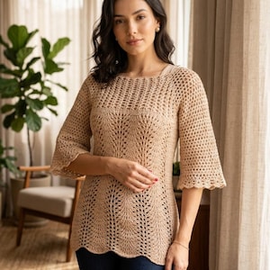 May include: A beige crochet top with a round neckline and three-quarter sleeves. The top features a detailed openwork pattern and a scalloped hem. The garment is made of a light, neutral-toned yarn, suitable for spring or summer wear.