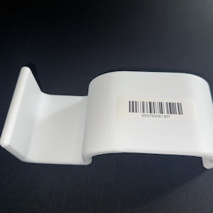 Op de afbeelding: Een witte kunststof displaystandaard met een gebogen, glad oppervlak en een verticale achtersteun. Aan de voorzijde is een rechthoekige sticker bevestigd met een zwarte streepjescode en de cijferreeks 693793061367 in zwarte inkt.