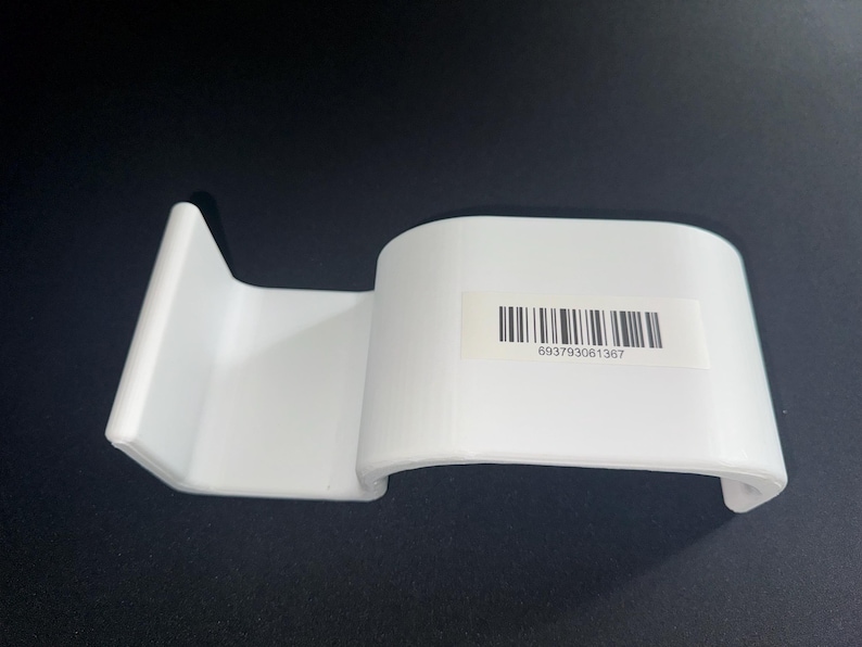 Op de afbeelding: Een witte kunststof displaystandaard met een gebogen, glad oppervlak en een verticale achtersteun. Aan de voorzijde is een rechthoekige sticker bevestigd met een zwarte streepjescode en de cijferreeks 693793061367 in zwarte inkt.