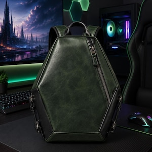 Puede incluir: Una mochila de forma hexagonal en color verde oscuro con una textura lisa similar al cuero. Presenta bordes negros, un asa superior y un cierre de cremallera diagonal único en el panel frontal con un tirador metálico.