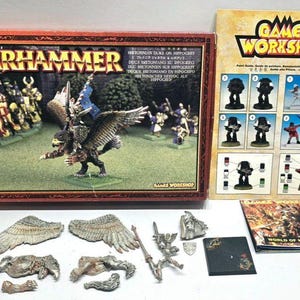 May include: A Warhammer miniature set featuring a box with the Warhammer logo and a miniature figure of a winged creature with a rider. Includes Games Workshop paint guide, miniature parts, and a booklet.