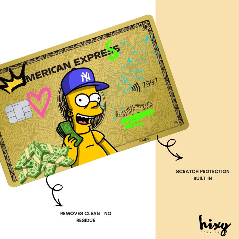 May include: A gold-colored American Express credit card featuring a cartoon character wearing a blue baseball cap. The card has a heart, crown, and dollar sign design. The card also has the text "AMERICAN EXPRESS" and "MEMBER SINCE".
