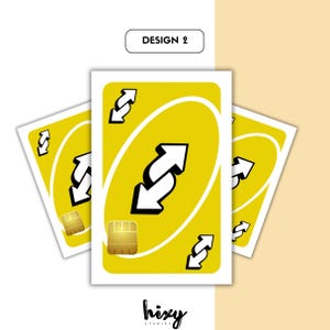 Puede incluir: Tres cartas de Uno amarillas con bordes blancos, con un gran s&iacute;mbolo de flecha invertida blanca y flechas m&aacute;s peque&ntilde;as. El texto "DESIGN 2" est&aacute; encima de las cartas. El logotipo de "hixy studios" est&aacute; en la parte inferior.