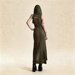 Pode incluir: Vestido maxi com capuz verde-oliva com design sem mangas e fenda lateral. A parte de tr&aacute;s do vestido apresenta detalhes de cortes horizontais. A modelo usa botas de plataforma pretas.