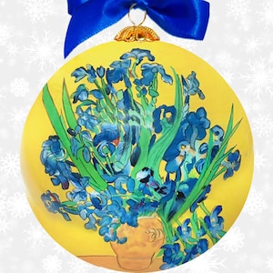 May include: A round, yellow Christmas ornament featuring a painting of blue irises in a vase. The ornament has a blue ribbon and gold-colored cap for hanging. The artwork is reminiscent of Van Gogh's style, with visible brushstrokes.