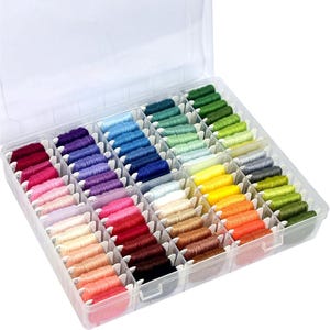 May include: A clear plastic organizer filled with colorful embroidery floss. The floss is arranged in neat rows, showcasing a spectrum of colors from deep reds and purples to vibrant blues, greens, and yellows. The threads are neatly wound, ready for crafting projects.