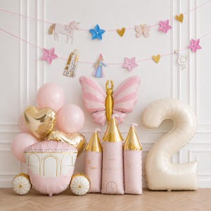 May include: A collection of party balloons including a large cream-colored number two, a pink butterfly, a carriage, and castle towers. A garland with paper cutouts of a unicorn, stars, hearts, a butterfly, and a swan hangs above the balloons.