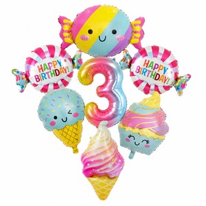 May include: A set of colorful foil balloons featuring a large number 3, two round candies with the text HAPPY BIRTHDAY, a large wrapped candy, two ice cream cones, and a cupcake. Each balloon has a smiling face and vibrant pastel colors.