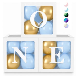 Peut inclure: Trois boîtes de présentation carrées blanches avec des fenêtres transparentes, contenant chacune des ballons bleu clair et or métallisé. Les boîtes présentent de grandes lettres blanches formant le mot ONE, empilées. Une palette de couleurs est visible.