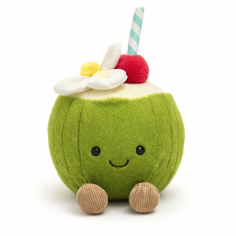 Op de afbeelding: Een groene pluche kokosdrank speelgoed met een lachend gezicht, bruine voetjes en een witte bloem, rode kers en gestreepte rietje bovenop. Het speelgoed is ontworpen om op een tropisch drankje te lijken.
