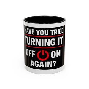 May include: A white ceramic coffee mug with a black interior and the text "HAVE YOU TRIED TURNING IT OFF ON AGAIN?" in white letters on a black and red background. The power button symbol is red.