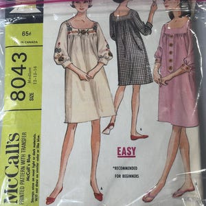 May include: Vintage McCall's sewing pattern 8043 for misses and junior smock dresses. The pattern includes three dress designs, with embroidery transfer options. The package is sealed in plastic and features illustrations of the dresses.