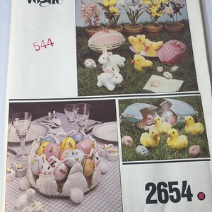 May include: A vintage Vogue pattern cover featuring Easter-themed decorations. The image showcases decorative eggs, bunnies, and chicks, along with floral arrangements. The cover includes the numbers "544" and "2654".