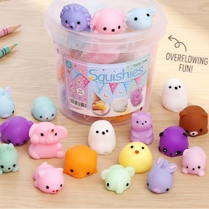 Op de afbeelding: Een verzameling kleurrijke, kleine, squishy speelgoedjes in verschillende dierlijke vormen, waaronder beren, konijnen en olifanten. Het speelgoed zit in een doorzichtige plastic container met het woord "Squishies" op de voorkant. De tekst "Overflowing Fun!" is ook zichtbaar.