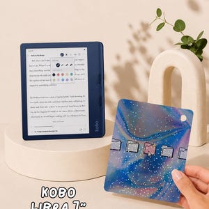 May include: A dark blue Kobo Libra 7-inch e-reader displaying a book page with a text settings menu. Beside it is a rectangular protective cover featuring a blue and purple holographic swirl pattern with white speckles and five folder icons.