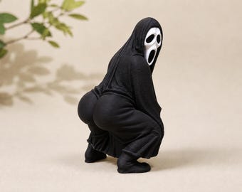 May include: A figurine of a character wearing a black hooded robe and a white mask with an elongated mouth and eye openings. The figure is in a crouching position, emphasizing a rounded, exaggerated posterior shape while looking back.