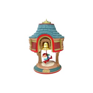 May include: A Christmas ornament featuring a bell tower design with a teal roof and red accents. A small elf figure is swinging from the golden bell. The base is a light blue-green color with a gold inscription.