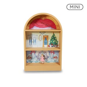 May include: A mini arched display shelf featuring a Nutcracker Ballet theme. The top section shows a stage with red curtains and text reading The Nutcracker Ballet. The middle shelf depicts a room with a Christmas tree, while the bottom shelf shows a candy land scene with a small figurine in a pink dress standing in the center.