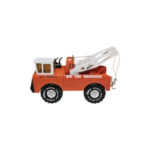 May include: A vintage orange Mighty Tonka tow truck featuring a white cab, a white boom crane, and black tires with white lettering. The side of the truck is printed with the text 24 HR SERVICE and the brand name Mighty Tonka in black lettering.