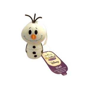 May include: A white ceramic Olaf Christmas tree ornament with a carrot nose, black buttons, and brown twig hair. Attached is a purple Hallmark Itty Bittys Disney tag with the text Olaf Christmas tree ornament decoration pour l'arbre de noël.