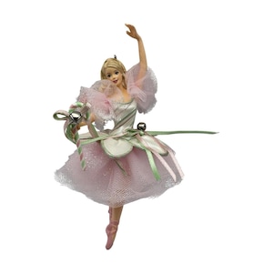 May include: A blonde ballerina figurine wearing a pink and white tulle dress with ruffled sleeves and a petal-shaped bodice. The figure holds a striped candy cane accessory adorned with a small silver bell and thin green and pink ribbons.