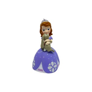 May include: A figurine of a girl with auburn hair wearing a silver tiara and a purple dress with white floral patterns, holding a small brown rabbit. The character has large blue eyes and is depicted in a standing pose with a wide skirt.