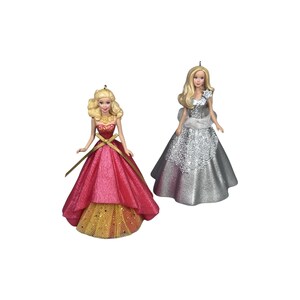 May include: Two decorative doll ornaments with blonde hair. One doll wears a strapless pink gown with a gold bodice accent and a layered gold tulle skirt. The second doll wears a silver glittery gown with a textured bodice and a white wrap.