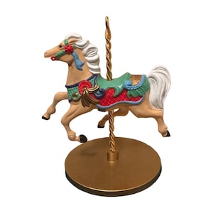Può includere: Statuetta di cavallo da giostra in beige, bianco, rosso, verde e oro. Il cavallo ha criniera e coda bianche, una sella rossa e verde e un palo dorato. La base è dorata.