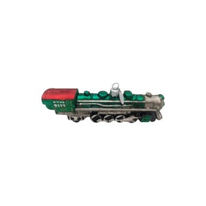 Peut inclure: Une décoration en verre en forme de locomotive avec une chaudière vert vif, une partie avant argentée métallique et une cabine rouge. Le train possède des roues noires et une attache argentée sur le dessus. Le numéro 4501 est inscrit en blanc.