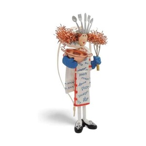 Può includere: Una statuetta decorativa da chef che indossa un grembiule bianco stampato con termini culinari come poach, roast e glaze. La figura ha capelli color rame, guanti blu, tiene in mano una ciotola di rame e una frusta, con una corona di posate argentate.