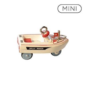 May include: A miniature boat ornament featuring a white hull with red accents, a red steering wheel, and a small red flag. The side of the boat is labelled with the text JOLLY ROGER in black. A silver metal hanging loop is attached to the top.